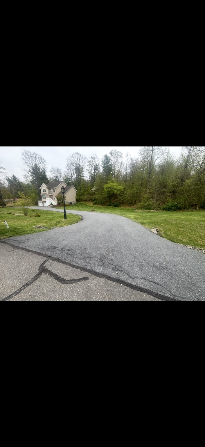 Driveway with weathered asphalt and visible cracks before sealcoating